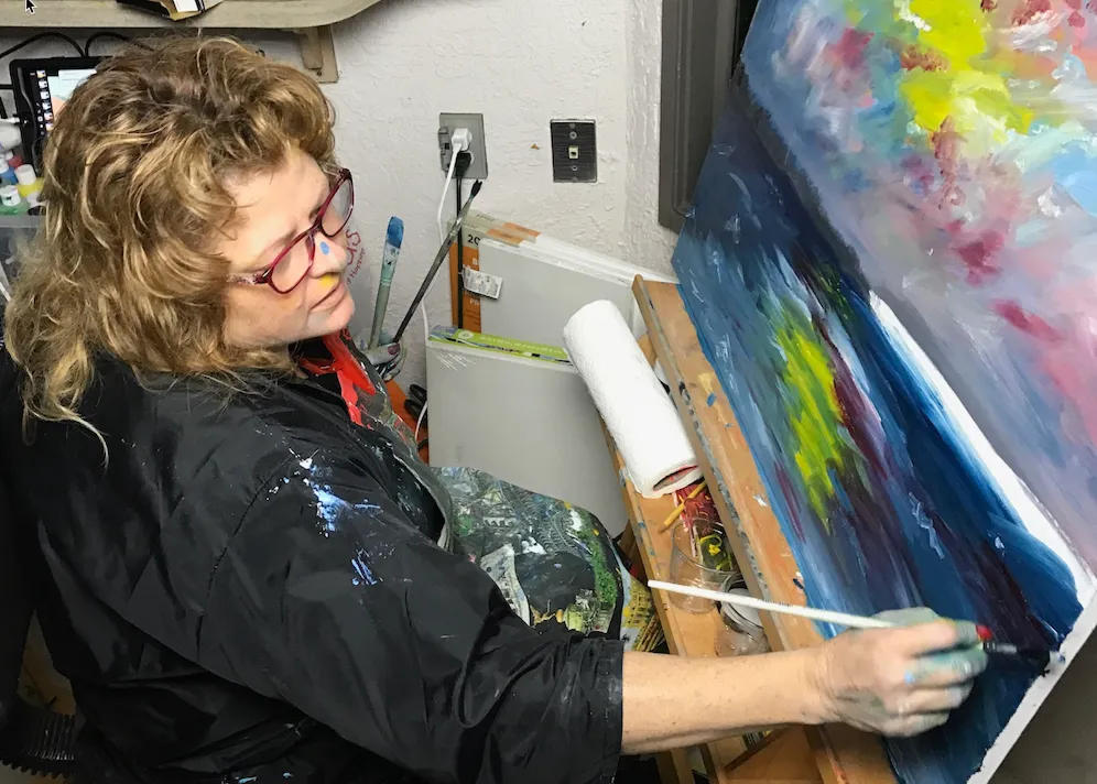 Tonya Maroney painting a colorful abstract on a large canvas in her studio